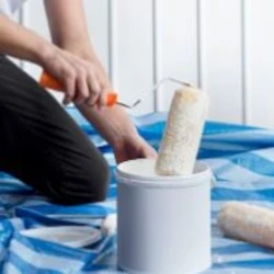 Homme qui prend de la peinture avec un rouleau dans un seau blanc